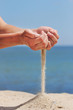 Foto: Hand throws sand on the seashore Hand throws sand on the seashore