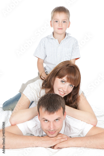 Photo: Smiling parents with little son lying on white background Smiling parents with little son lying on white background