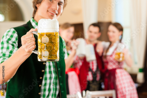 Photo: Young people in traditional Bavarian Tracht in restaurant or pub Young people in traditional Bavarian Tracht in restaurant or pub
