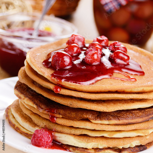 Photo: Delicious pancakes with raspberries on the wooden kitchen table Delicious pancakes with raspberries on the wooden kitchen table