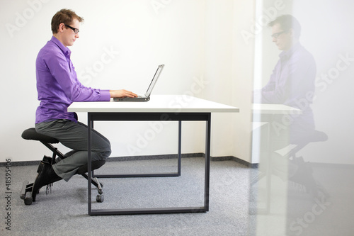 Photo: correct sitting position at workstation. man on kneeling chair correct sitting position at workstation. man on kneeling chair