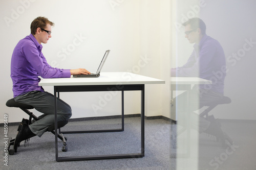 Photo: bad sitting posture at workstation. man on kneeling chair bad sitting posture at workstation. man on kneeling chair