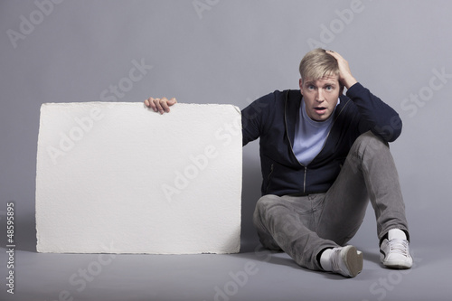 Photo: Surprised man holding white blank signboard. Surprised man holding white blank signboard.