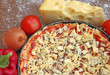uncooked pizza with ingredients on wooden background, close-up