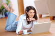 Young woman with laptop and a cup of coffee on the floor