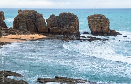Photo: Cliffs at beach with waves crushing against them Cliffs at beach with waves crushing against them