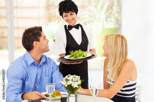 Photo: happy waitress serving customers in restaurant happy waitress serving customers in restaurant