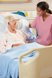 Nurse Talking To Senior Female Patient In Hospital Bed