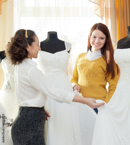 Photo: shop consultant helps girl chooses white bridal outfit shop consultant helps girl chooses white bridal outfit