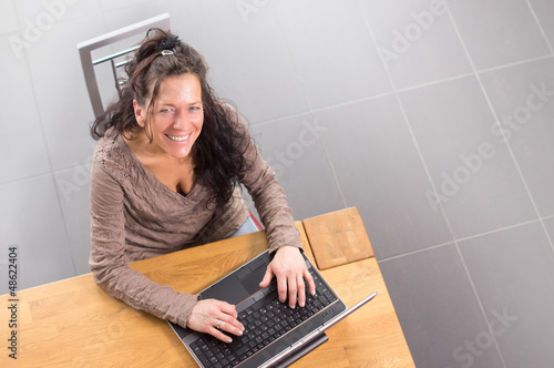 Photo: Frau sitzt lachend vor Notebook Frau sitzt lachend vor Notebook