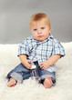 Little boy sitting on white carpet on gray background