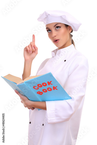 Photo: Portrait of young woman chef with cook book isolated on white Portrait of young woman chef with cook book isolated on white