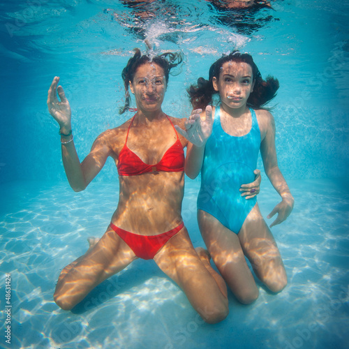 Photo: Mother and daughter having fun underwater in swimming pool. Mother and daughter having fun underwater in swimming pool.