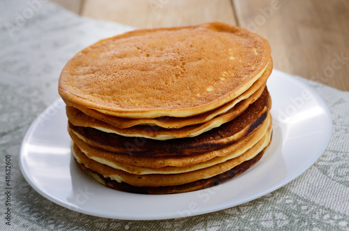 Photo: White plate with pankakes stack on the kitchen table White plate with pankakes stack on the kitchen table