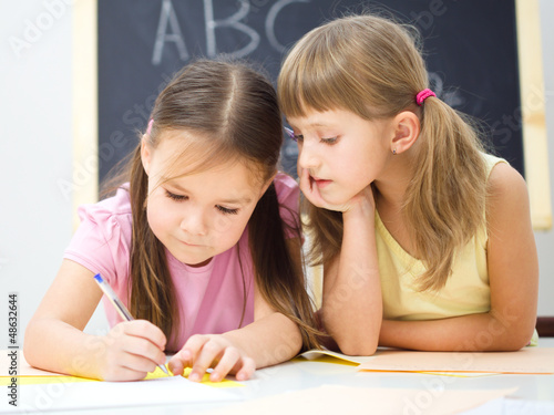 Photo: Little girls are writing using a pen Little girls are writing using a pen
