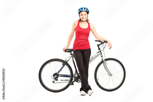 Photo: Female biker with helmet posing next to a mountain bike Female biker with helmet posing next to a mountain bike