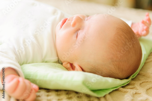 Photo: Cute newborn baby sleeping in bed Cute newborn baby sleeping in bed