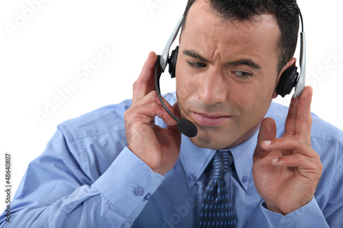 Photo: Businessman struggling to hear his headset Businessman struggling to hear his headset