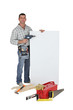 Carpenter using drill to point to poster