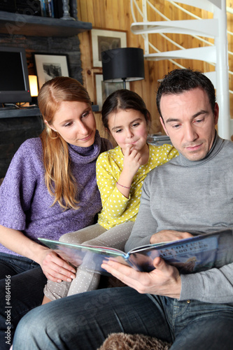 Photo: Young family going through photo album Young family going through photo album