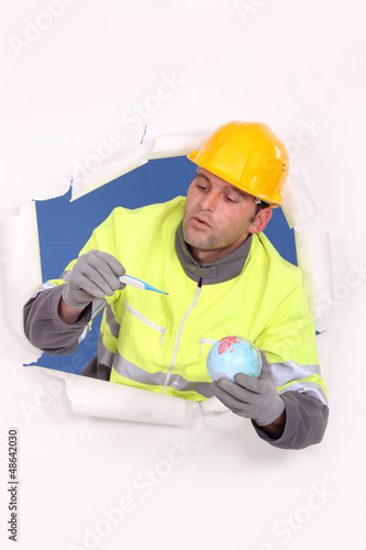 Photo: Builder holding globe and pregnancy test Builder holding globe and pregnancy test