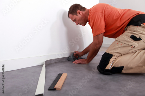 Photo: Man putting down linoleum on a baseboard Man putting down linoleum on a baseboard