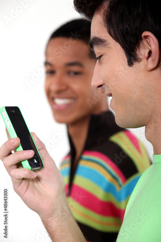 Photo: Teen male teenagers looking at text message Teen male teenagers looking at text message