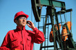 Oil Worker Using Cell Phone Next to Pumpjack
