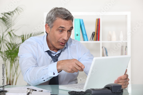 Photo: Businessman laughing in front of a laptop Businessman laughing in front of a laptop