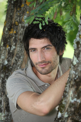 Photo: Man leaning against tree Man leaning against tree