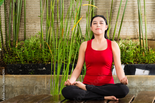 Photo: Asian woman doing yoga in tropical setting Asian woman doing yoga in tropical setting
