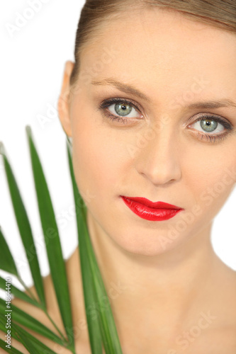 Photo: Blond woman holding green plant leaf Blond woman holding green plant leaf