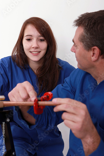 Photo: Plumber instructing young female trainee Plumber instructing young female trainee