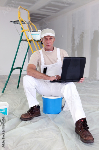 Photo: Painter taking a break to use his laptop Painter taking a break to use his laptop