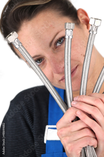 Photo: Female plumber holding selection of metal pipes Female plumber holding selection of metal pipes