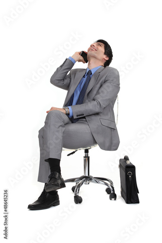 Photo: Man sitting in a chair by phone Man sitting in a chair by phone
