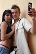 Couple stood by wall taking self-portrait on camera phone