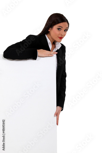 Photo: Businesswoman standing behind a white sign Businesswoman standing behind a white sign