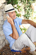 Old man sat by stone wall whilst on vacation