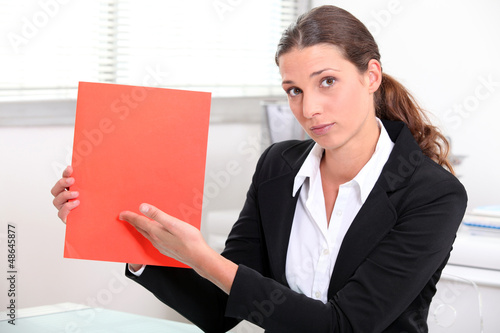 Photo: Woman at desk showing document Woman at desk showing document