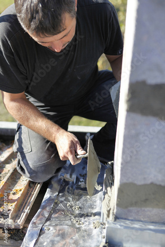 Photo: Mason using trowel to spread cement on wall Mason using trowel to spread cement on wall