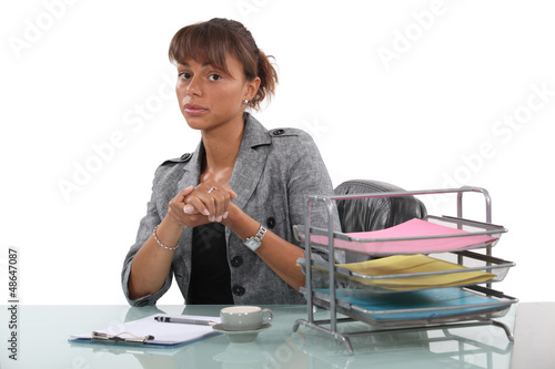 Photo: Woman sitting in office with coffee cup Woman sitting in office with coffee cup