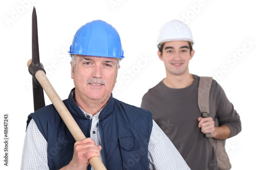 Photo: mature manual worker and young apprentice in background mature manual worker and young apprentice in background