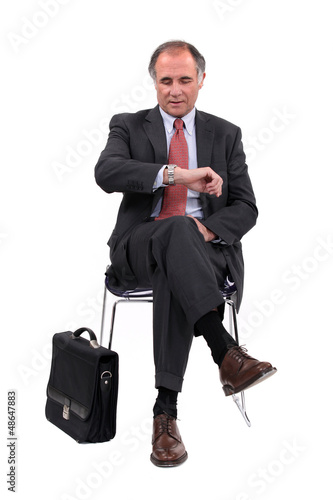 Photo: businessman consulting his watch businessman consulting his watch