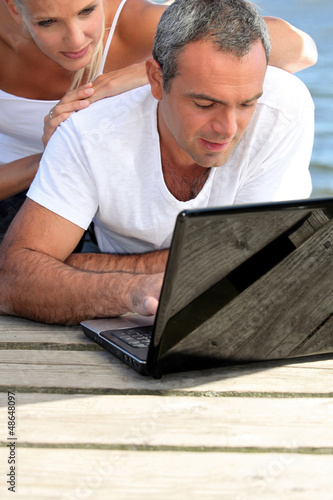 Photo: Man lying with a woman behind computer Man lying with a woman behind computer