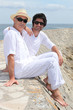 Grownup father and son sitting on a harbor wall