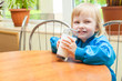 Little funny girl is drinking milk