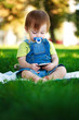 baby is playing with phone on the green grass