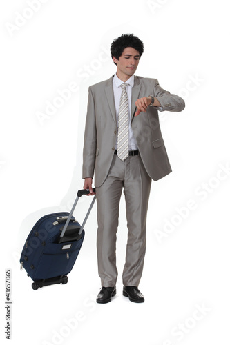 Photo: Businessman with a suitcase looking at his watch Businessman with a suitcase looking at his watch