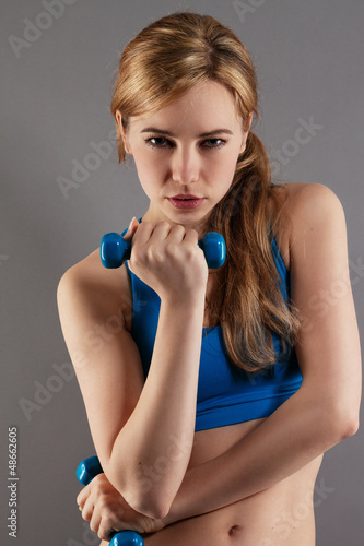 Photo: junge ernste sportlerin mit fitness hanteln junge ernste sportlerin mit fitness hanteln